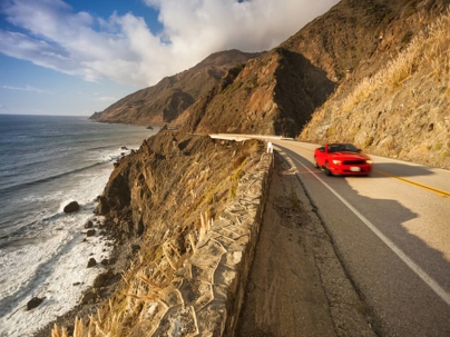 a red convertible traveling on highway 1